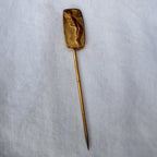 Back of brass lady stick pin showing patina