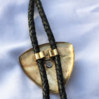 Back of brass eagle bolo tie showing cord hardware