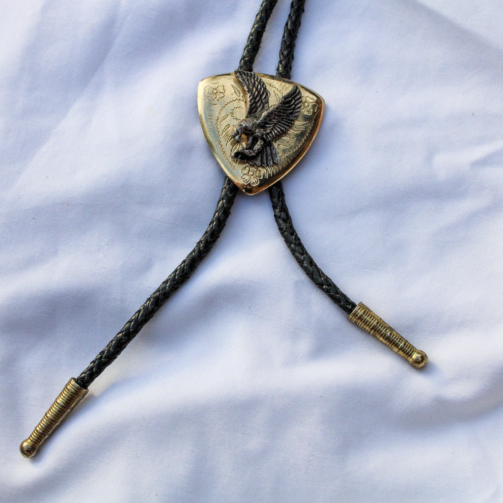 Full view of brass eagle bolo tie with braided cord and tips