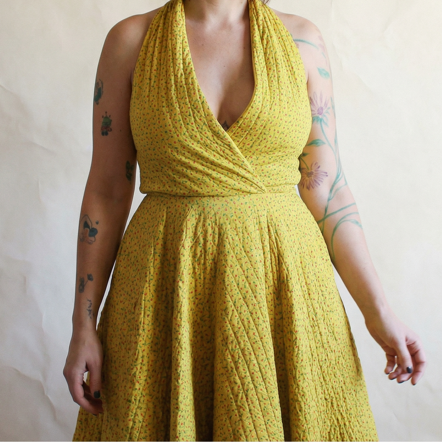 Woman wearing a yellow knitted dress against a plain background